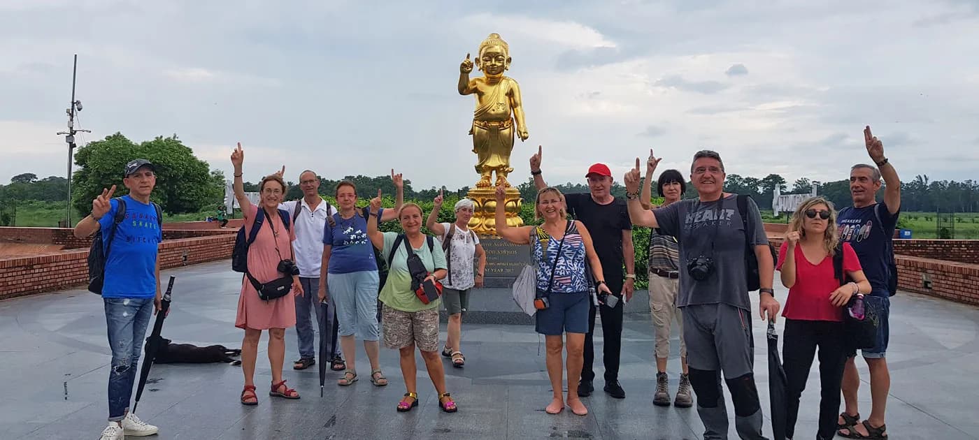 Group of international tourists posing in front of the golden Baby Buddha statue in Lumbini, Nepal.