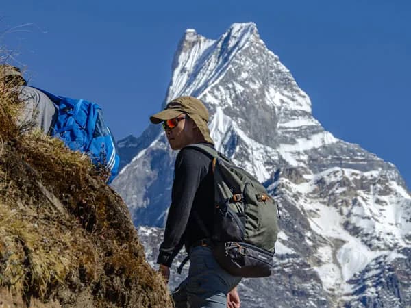Trekker hiking along a ridge with the iconic snow-covered peak of Mount Machapuchare (Fishtail) in the background during a 4-day Mardi Himal trek in Nepal