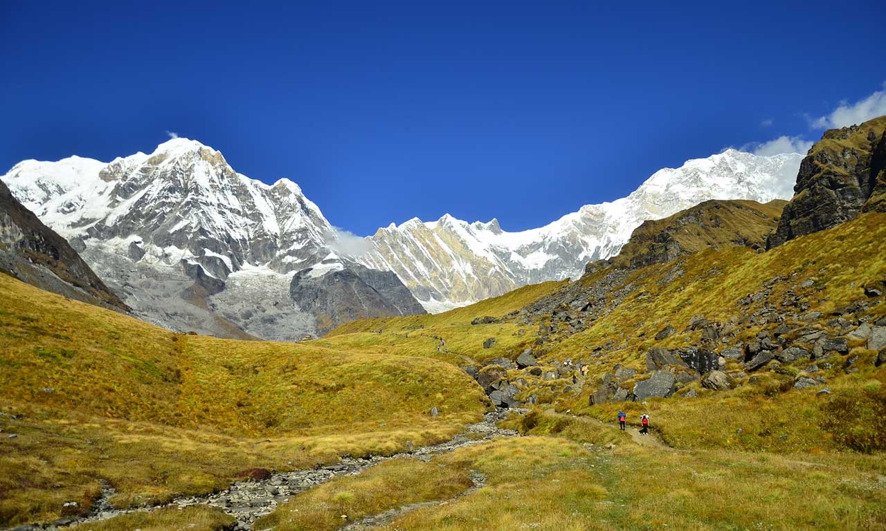 Panoramic view of Annapurna Base Camp with snow capped peaks and trekkers in the foreground