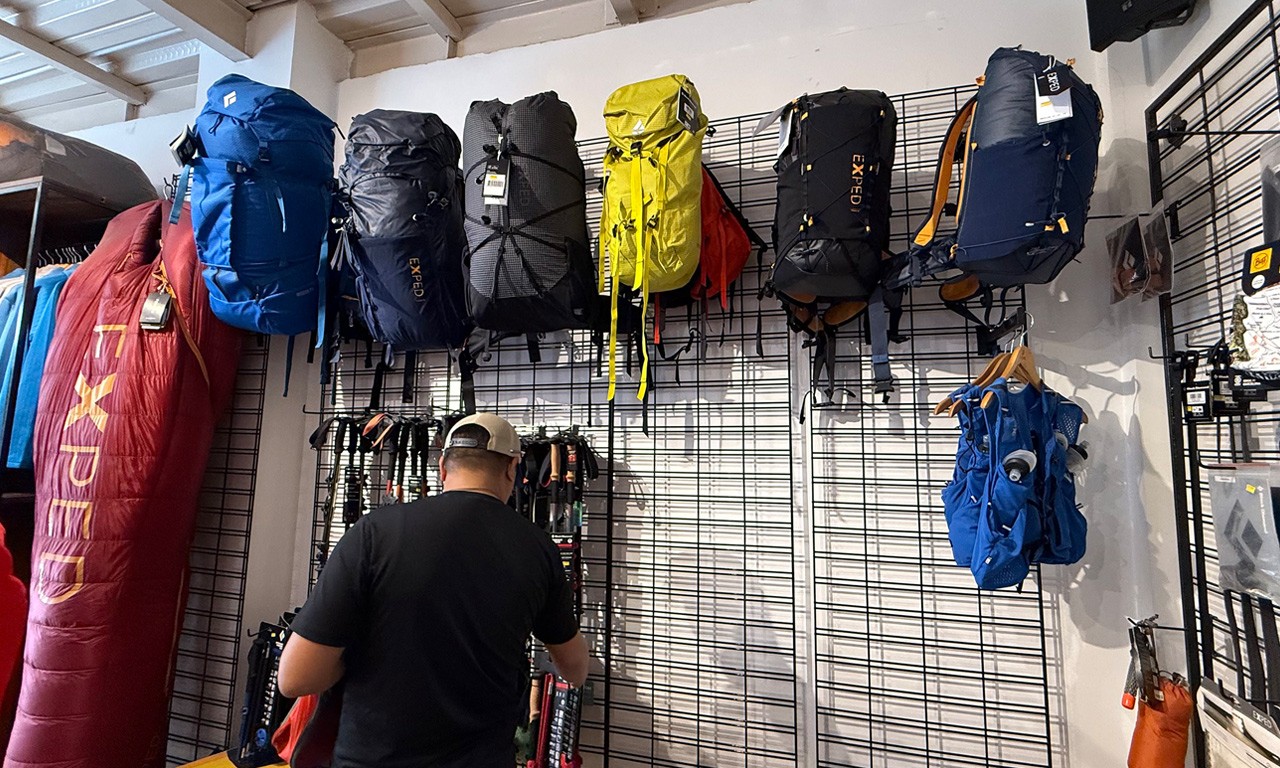 A traveler browsing high-quality trekking backpacks and hiking poles from brands like Exped and Black Diamond in a Thamel gear store.