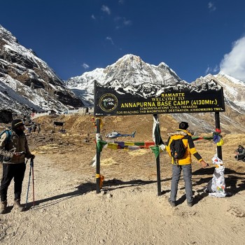 Trekkers celebrating at the official Annapurna Base Camp welcome sign at 4,130m.